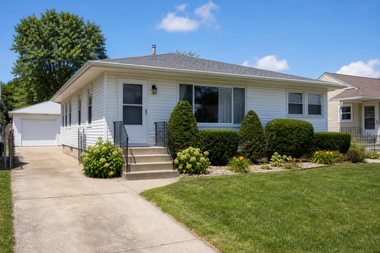 single-story suburban house with driveway and front lawn under a blue sky
